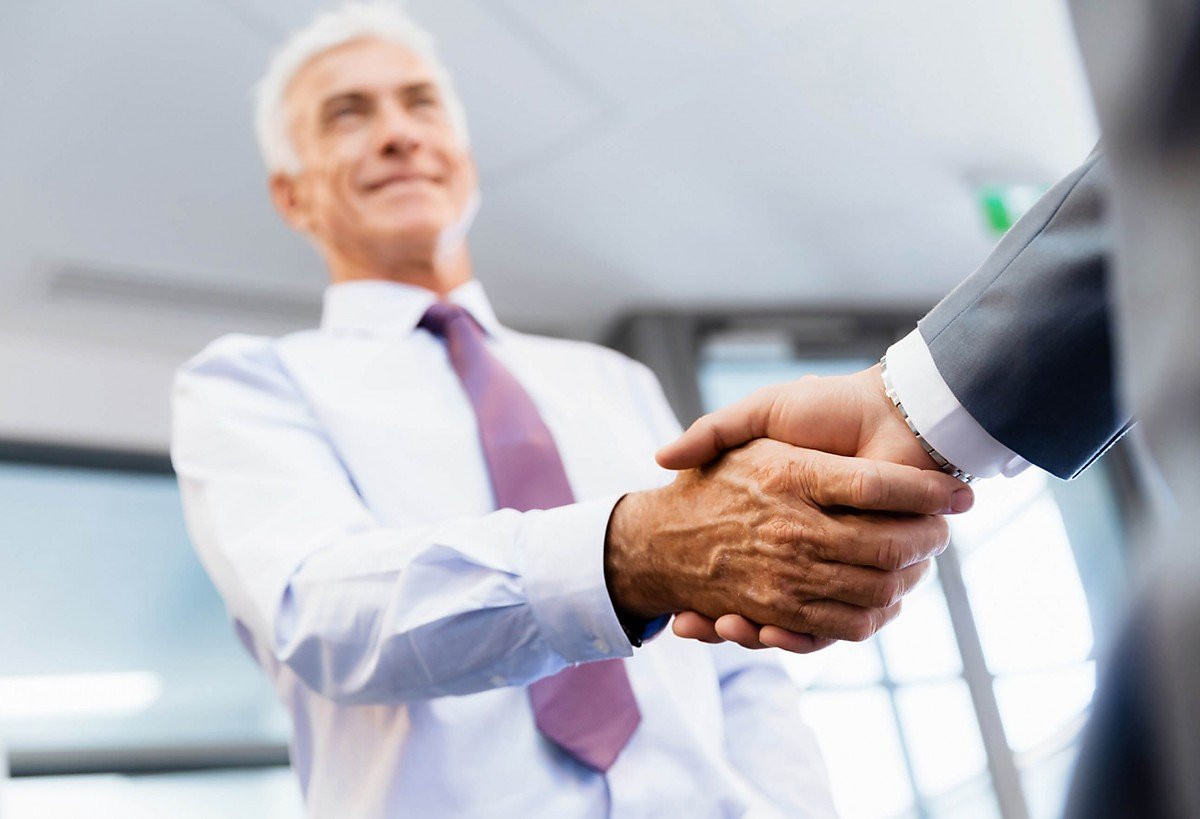 Immobilienmakler in Business-Kleidung sch�ttelt einem Kunden die Hand, symbolisiert eine erfolgreiche Immobilienvermittlung