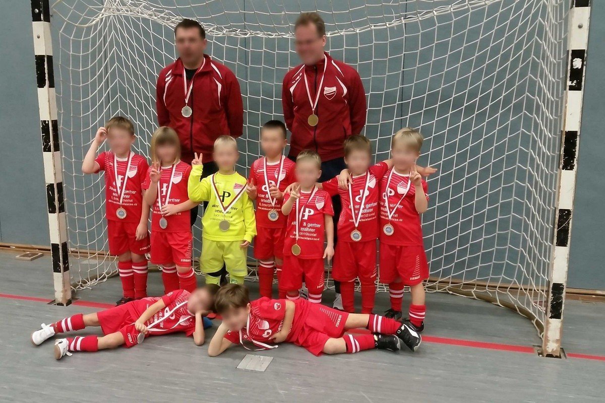 Jugendarbeit in Braunschweig – Sportförderung durch Adner & Partner Immobilien Jugendfußballmannschaft in roten Trikots mit Trainern bei einem Hallenturnier als Beispiel für die regionale Sportförderung von Adner & Partner Immobilien