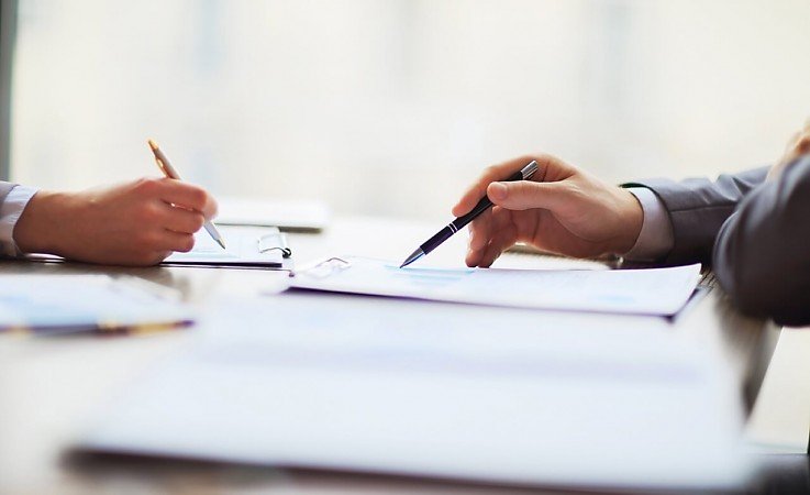 Zwei Personen unterzeichnen einen Kaufvertrag f�r eine Eigentumswohnung an einem Tisch