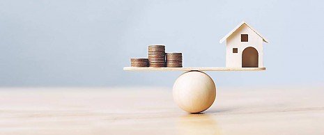 >Geld und Haus auf der Waage